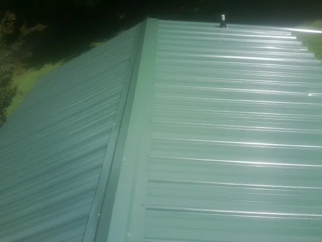 New green metal panels meeting at the ridge of a roof — Flat Roof Repair work by our crew in Mapleton